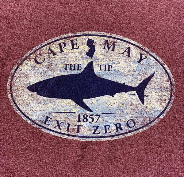 Silhouette of a shark and the state of New Jersey. Text: The Tip. 1857. Cape May. Exit Zero